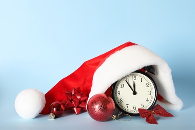 Photo of Vintage alarm clock with Christmas decor on light blue background. New Year countdown