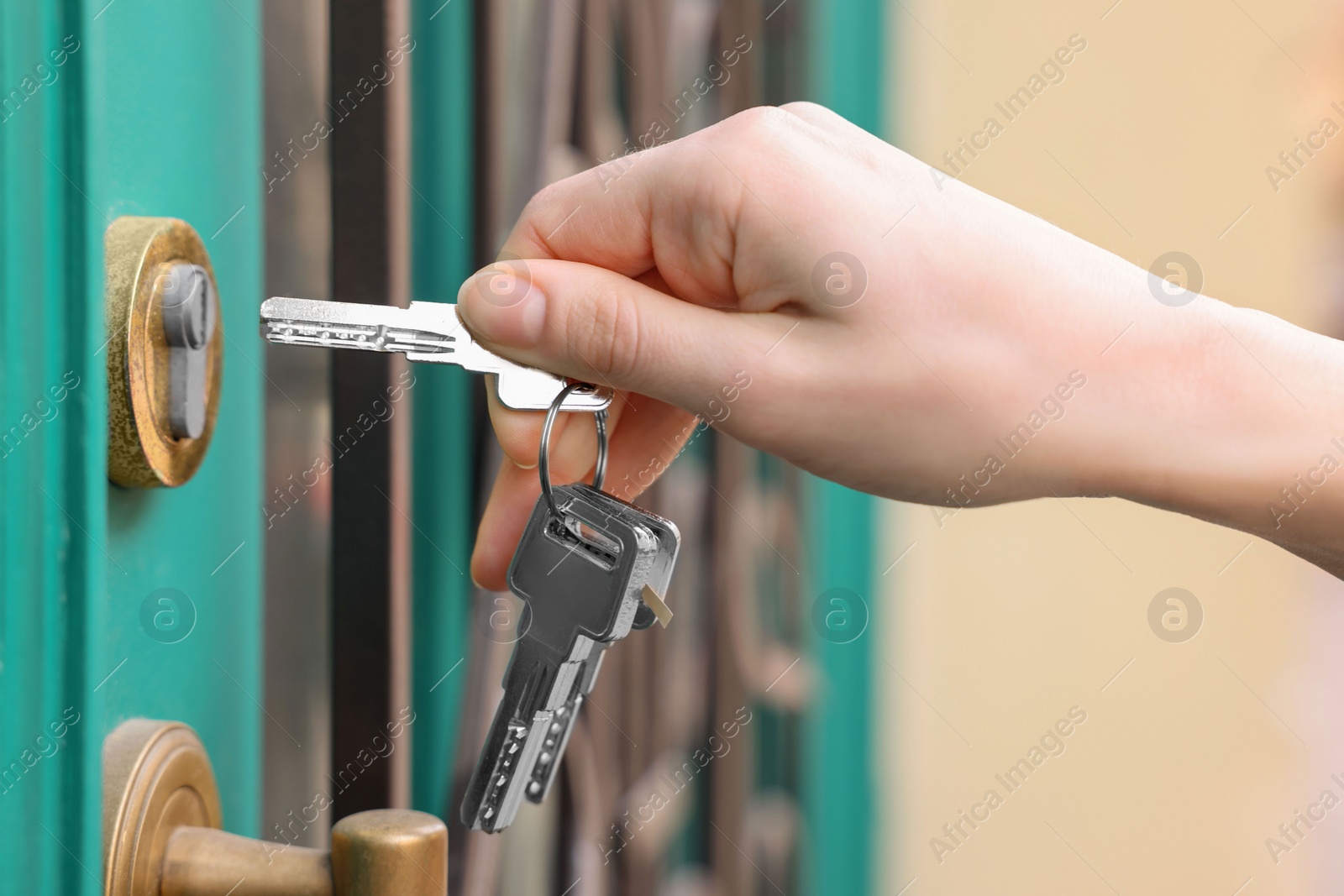 Photo of Woman opening door with key outdoors, closeup