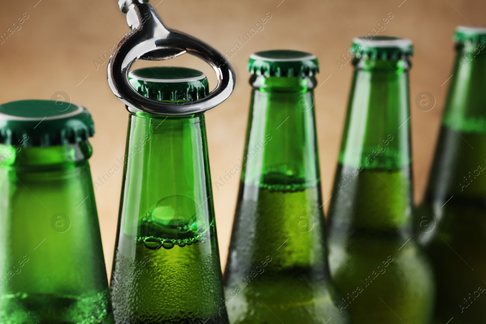 Photo of Opening bottle of beer on light brown background, closeup. Space for text