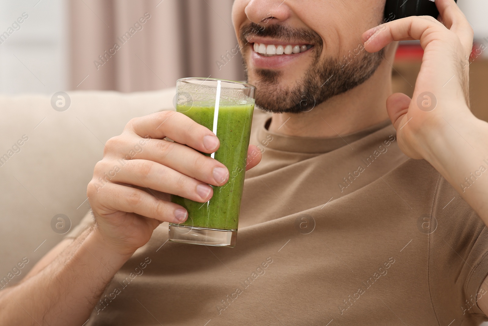 Photo of Man holding glass of delicious smoothie indoors, closeup