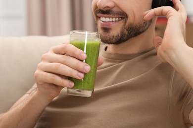 Man holding glass of delicious smoothie indoors, closeup