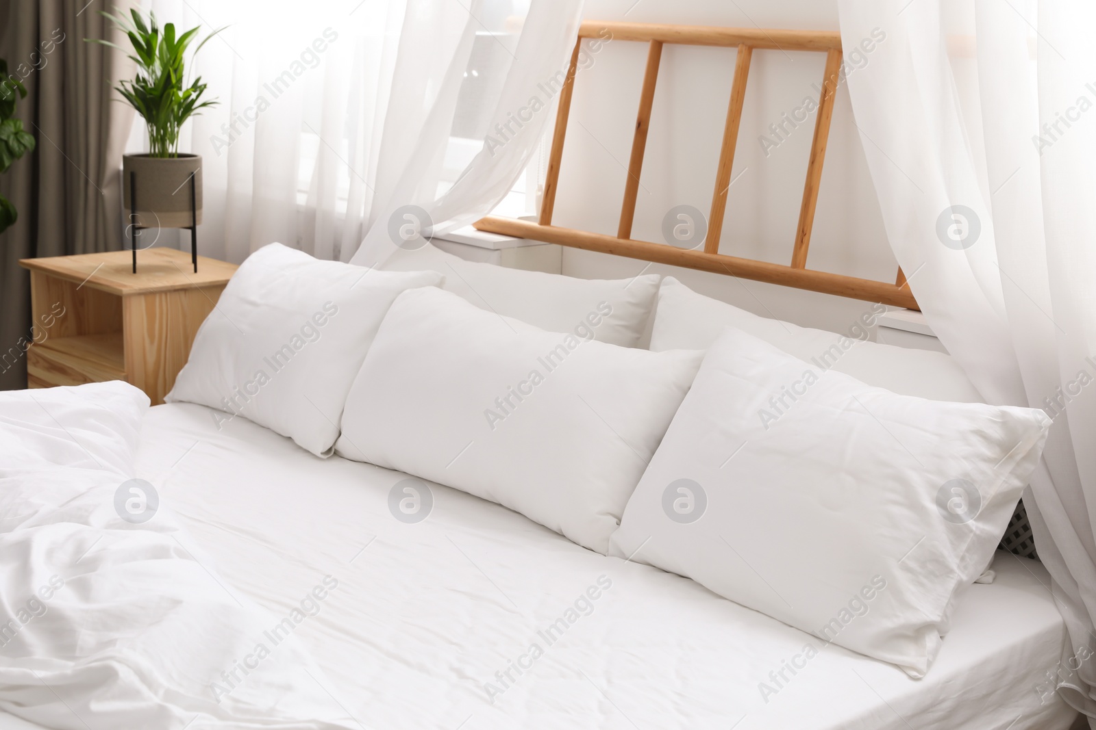 Photo of Comfortable bed with soft pillows in room interior