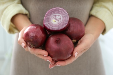 Photo of Woman holding red onions on blurred background, closeup