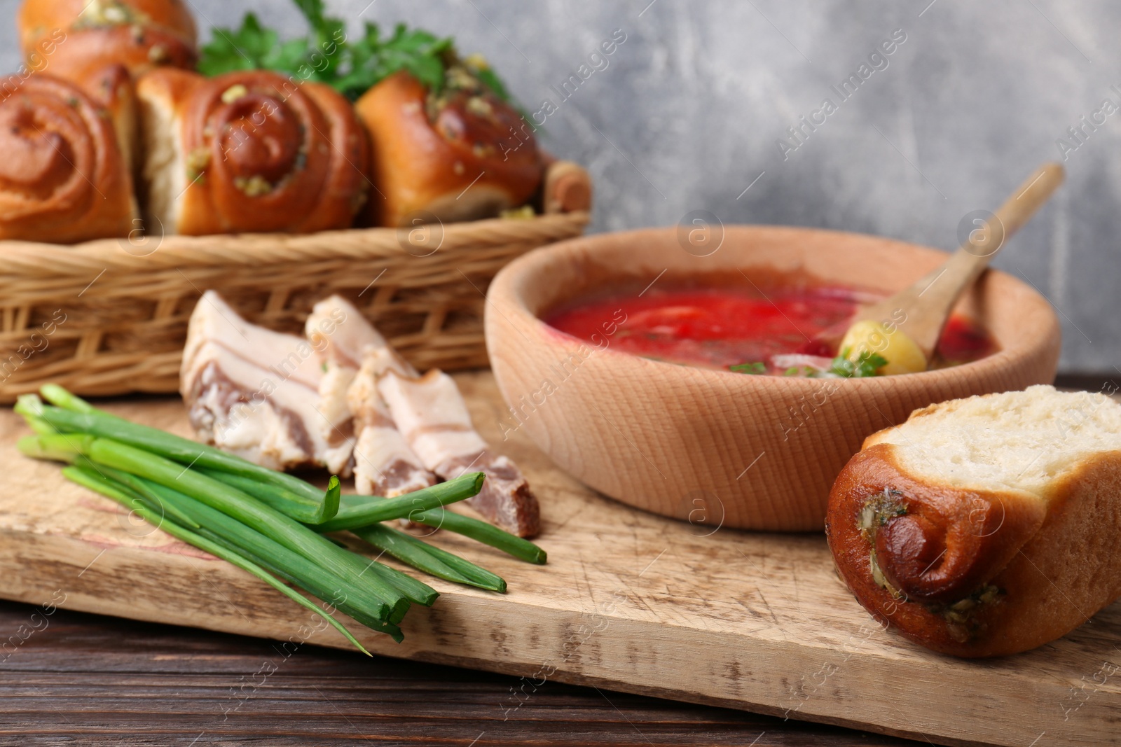 Photo of Delicious borsch served with pampushky and salo on wooden table, closeup. Traditional Ukrainian cuisine