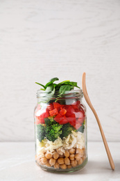 Photo of Healthy salad in glass jar on white table