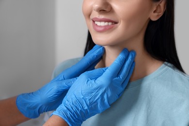 Endocrinologist examining thyroid gland of patient indoors, closeup