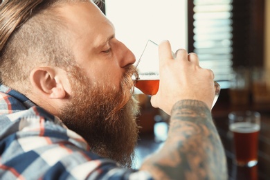 Photo of Bearded man drinking tasty beer in pub