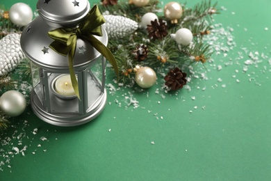 Christmas lantern with burning candle and festive decor on green background
