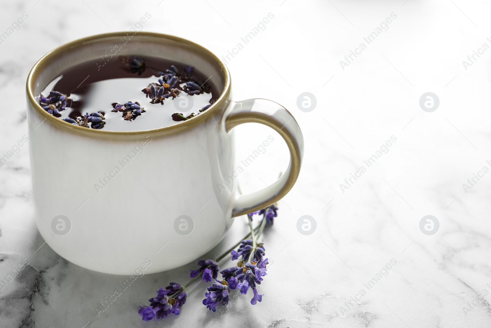 Photo of Fresh delicious tea with lavender and beautiful flowers on white marble table. Space for text