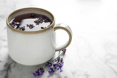 Photo of Fresh delicious tea with lavender and beautiful flowers on white marble table. Space for text