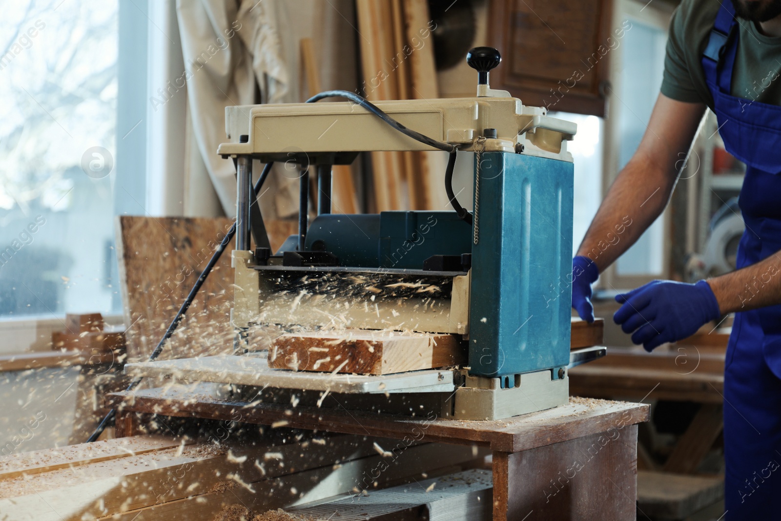 Photo of Professional carpenter working with grinding machine in shop, closeup