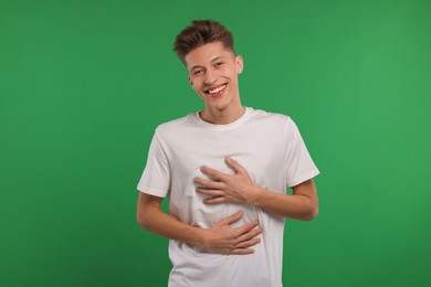 Photo of Portrait of young man laughing on green background
