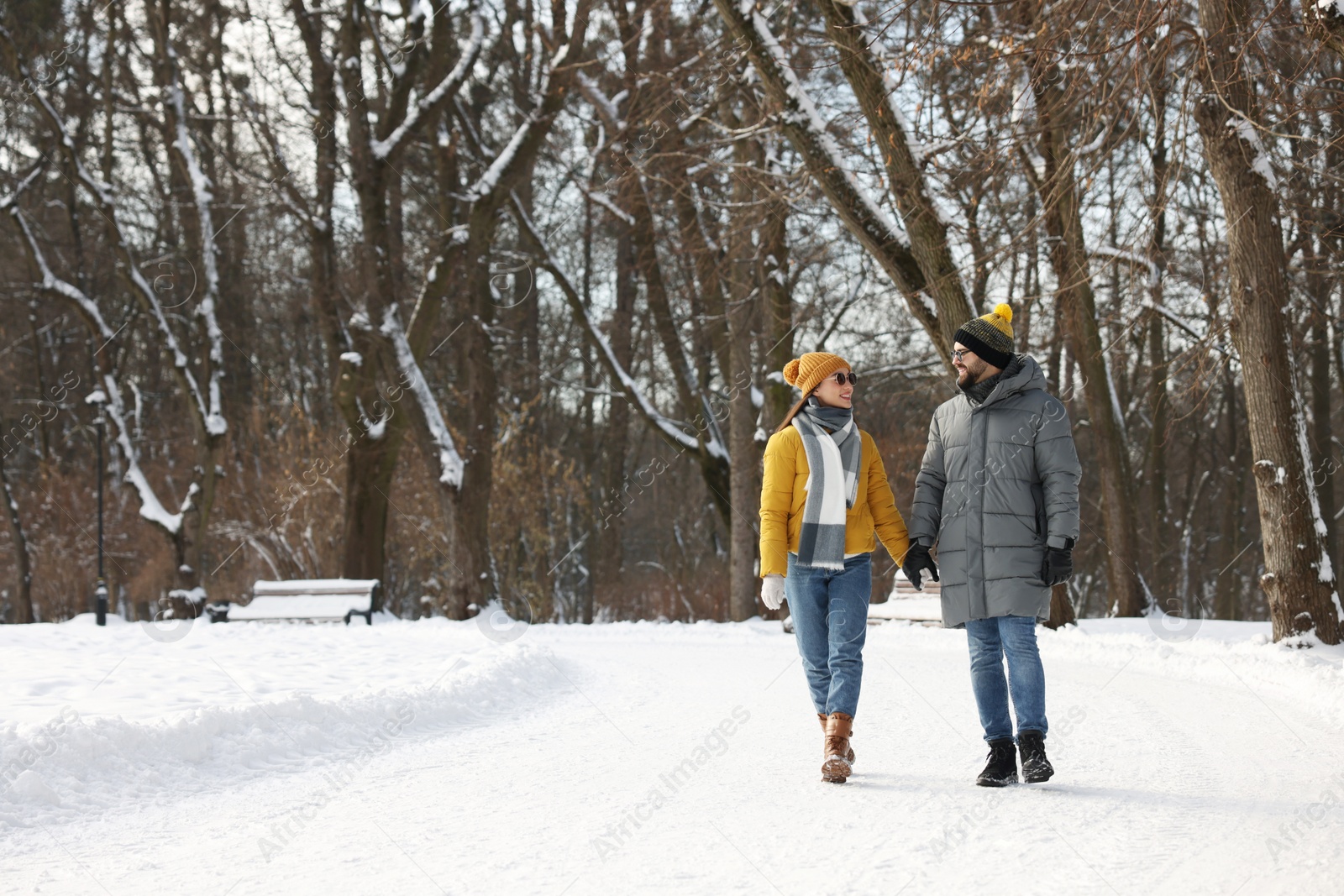 Photo of Beautiful happy couple walking in snowy park on winter day