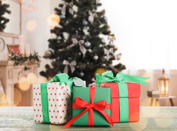 Image of Christmas gift boxes on wooden table in room, bokeh effect