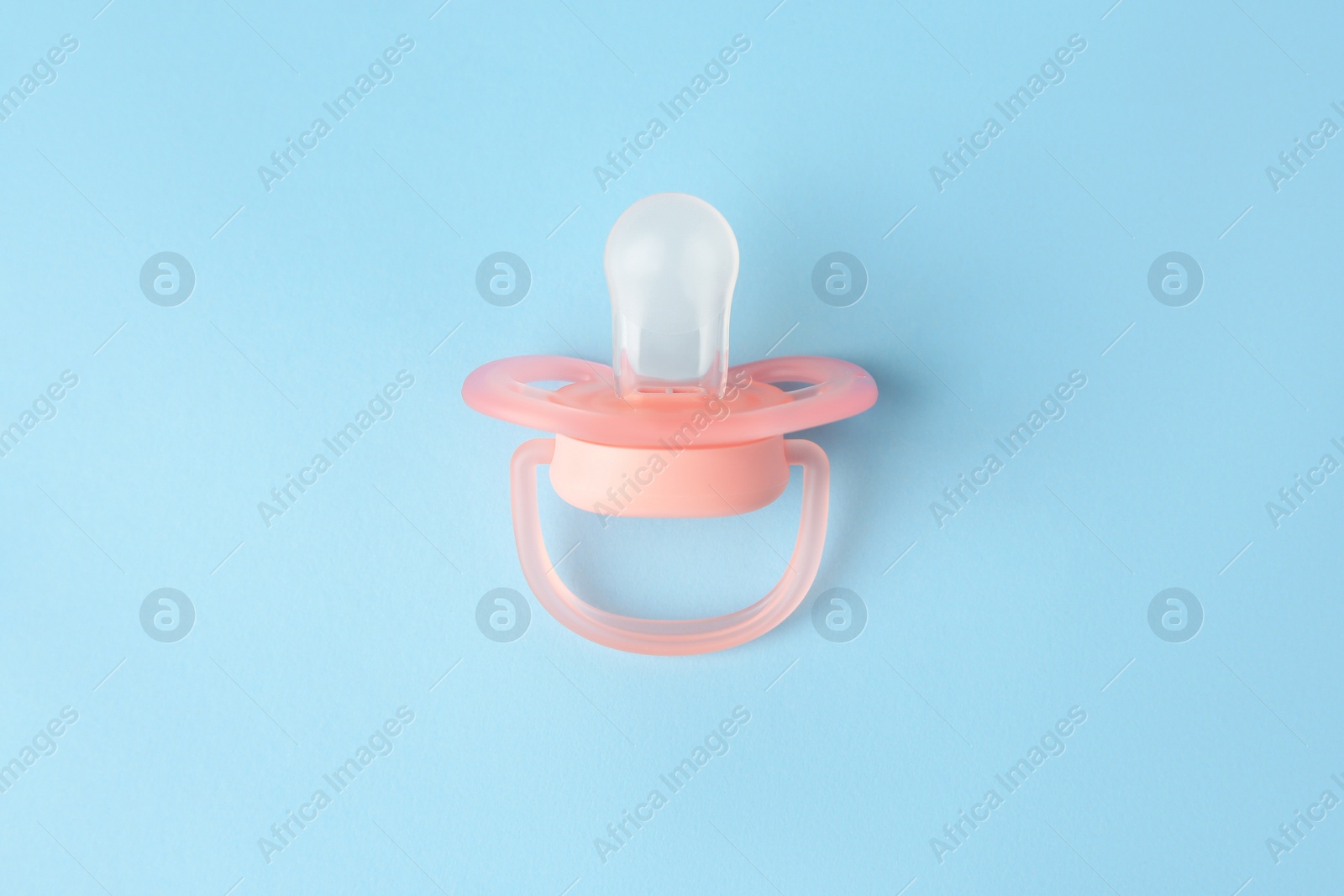 Photo of One new baby pacifier on light blue background, top view