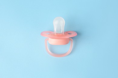 One new baby pacifier on light blue background, top view