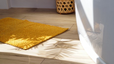 Soft bath mat near tub on wooden floor in bathroom