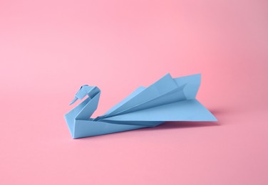 Photo of Origami art. Beautiful paper swan on pink background