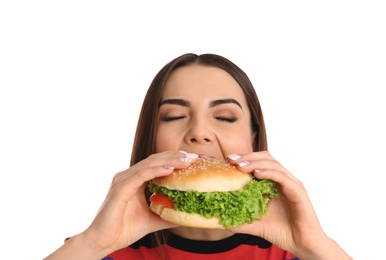 Young woman eating tasty burger on white background