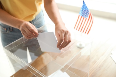 Woman putting ballot paper into box at polling station, closeup