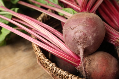 Photo of Raw ripe beets in wicker bowl on table, closeup