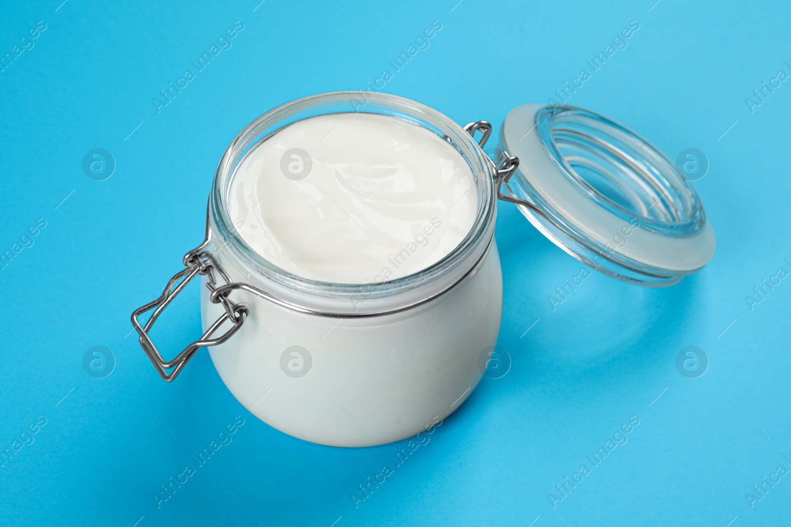 Photo of Jar of tasty organic yogurt on light blue background