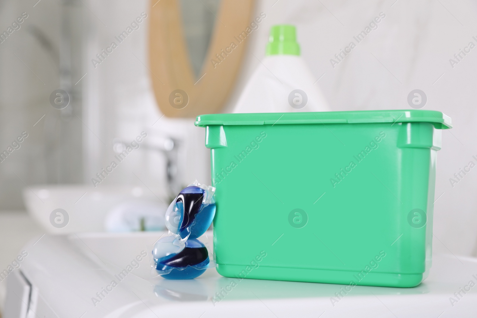 Photo of Laundry detergent capsules and package on washing machine indoors, closeup. Space for text