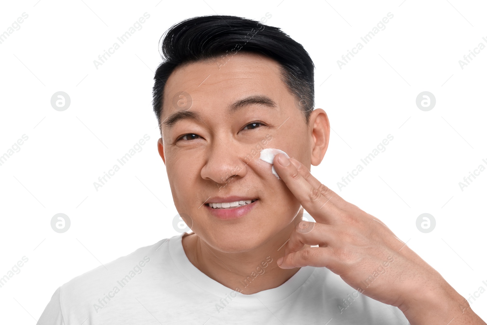 Photo of Handsome man applying cream onto his face on white background