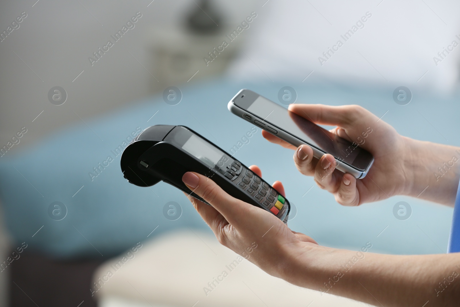 Photo of Woman using modern payment terminal with mobile phone indoors, closeup