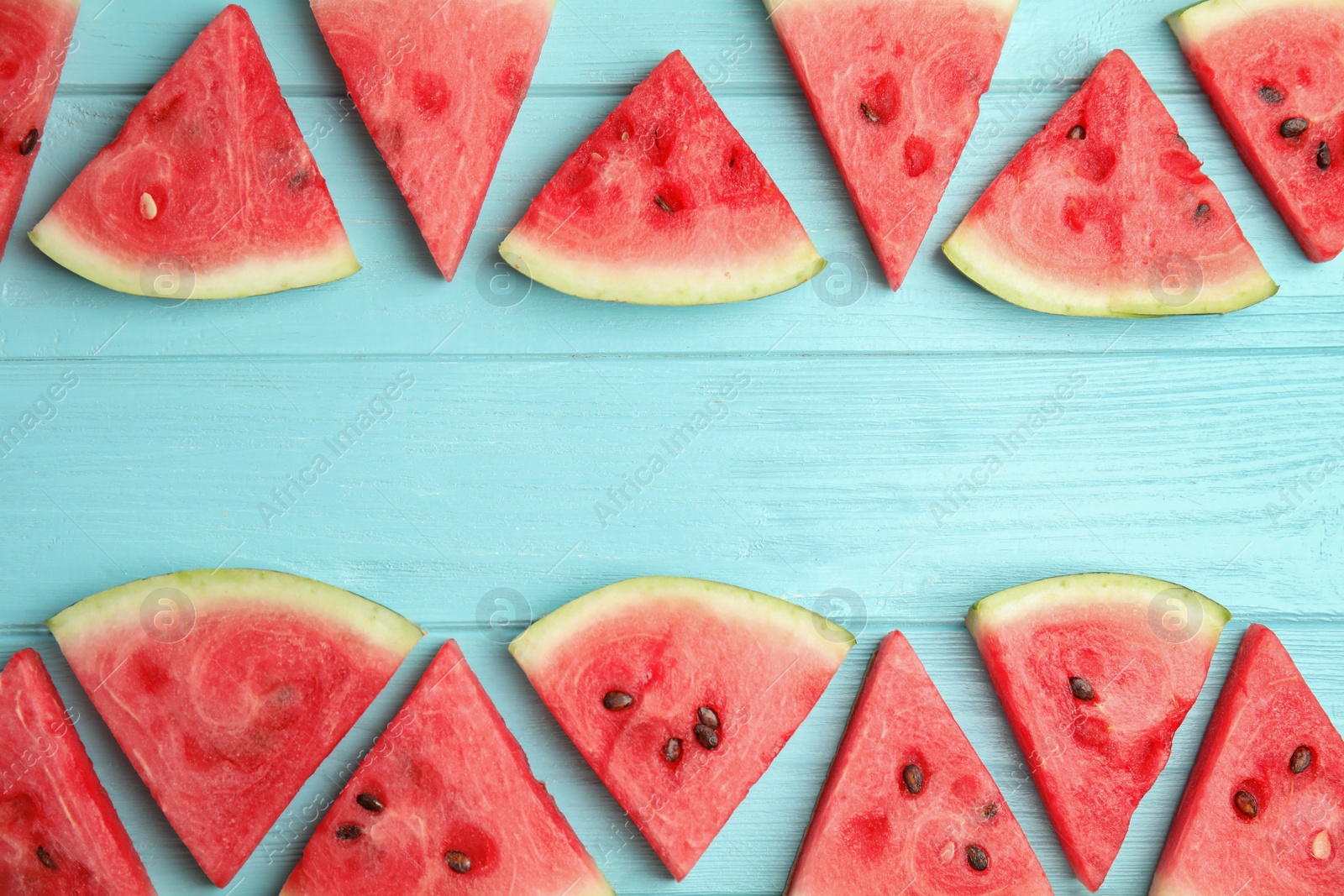 Photo of Frame made with slices of ripe watermelon on light blue wooden table, flat lay. Space for text