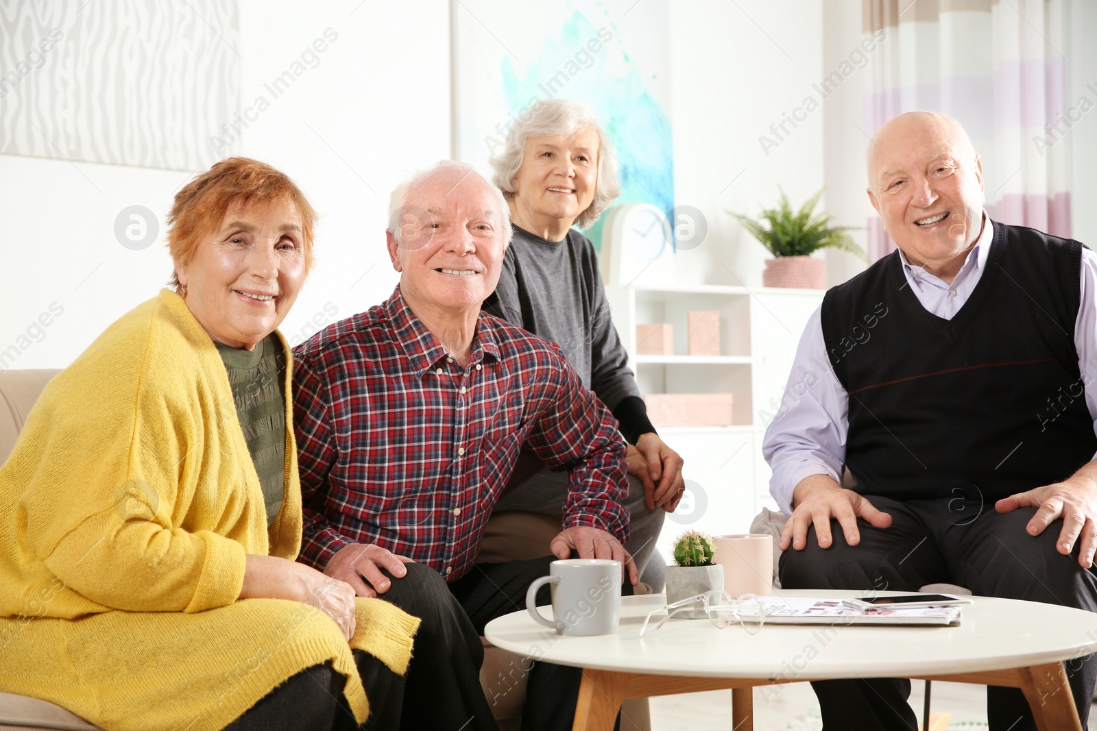 Photo of Portrait of happy elderly people at table in living room