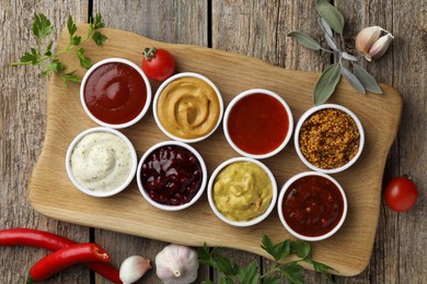 Photo of Different tasty sauces in bowls and ingredients on wooden table, top view
