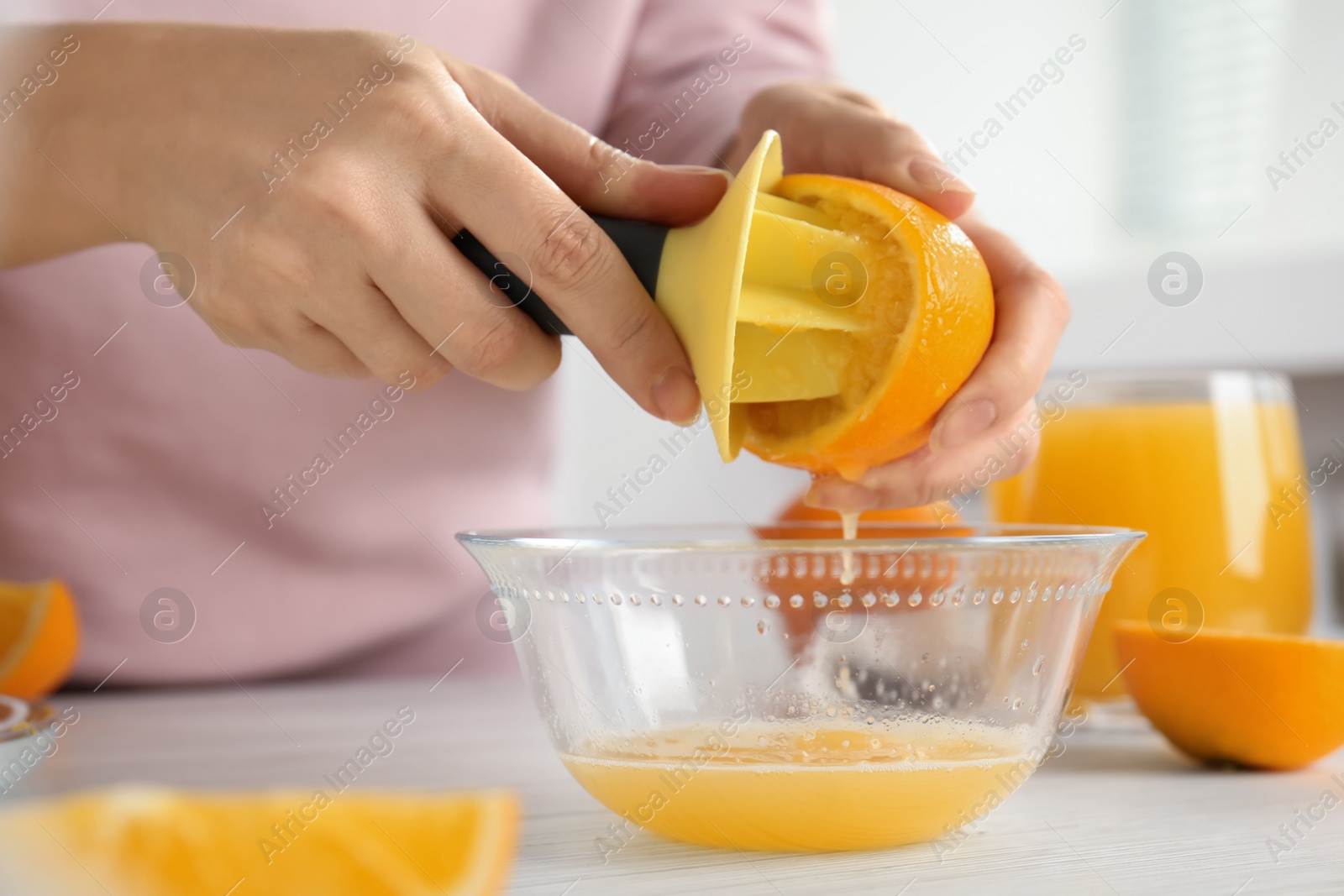 Photo of Woman squeezing orange juice at wooden table, closeup