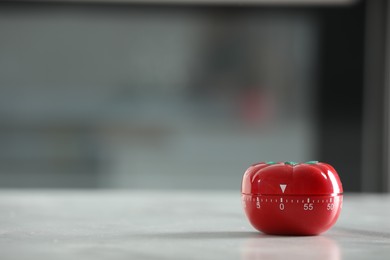 Photo of Kitchen timer in shape of tomato on light grey table against blurred background. Space for text