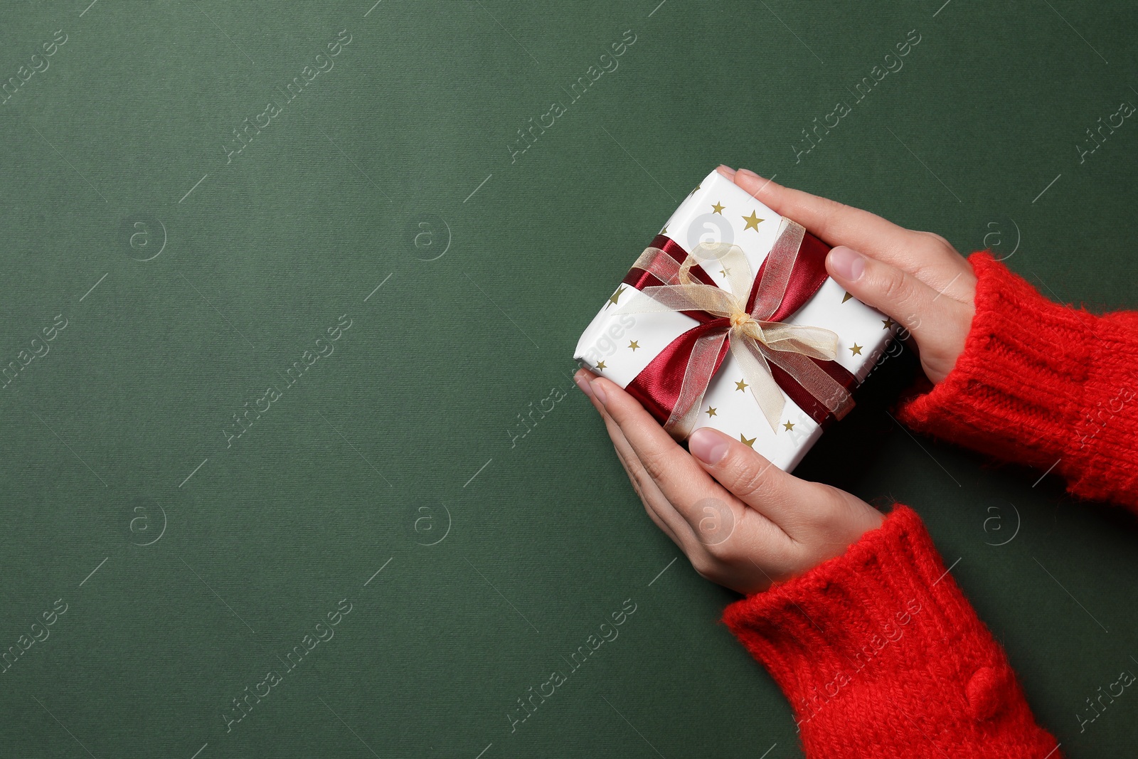 Photo of Woman with Christmas gift on green background, top view. Space for text