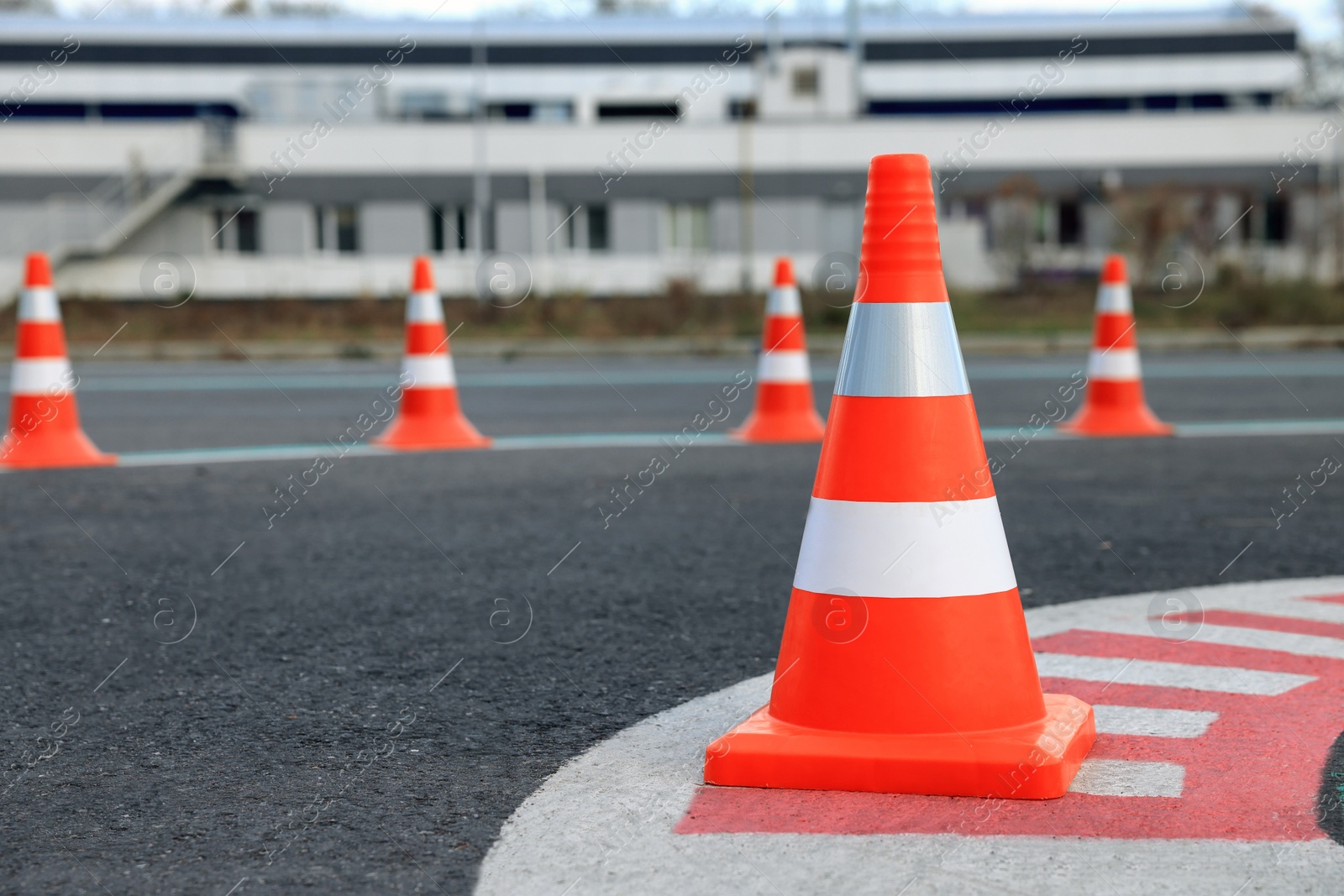 Photo of Driving school test track with marking lines, focus on traffic cone