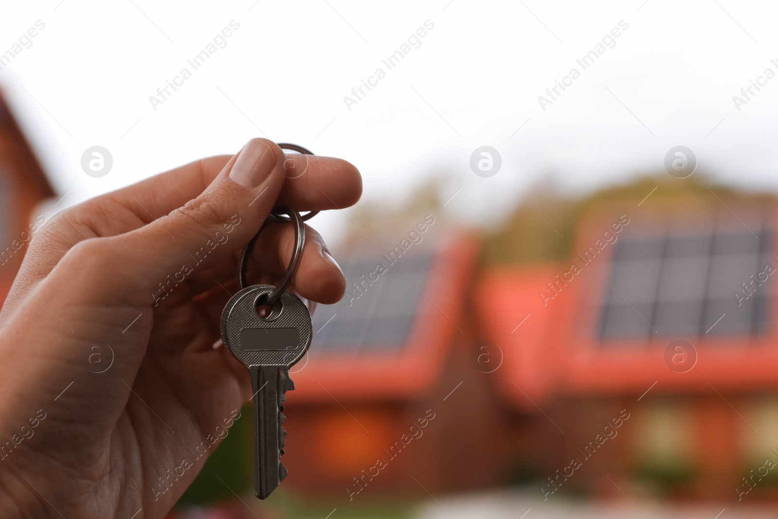 Photo of Real estate agent holding keys to new house outdoors, closeup. Space for text