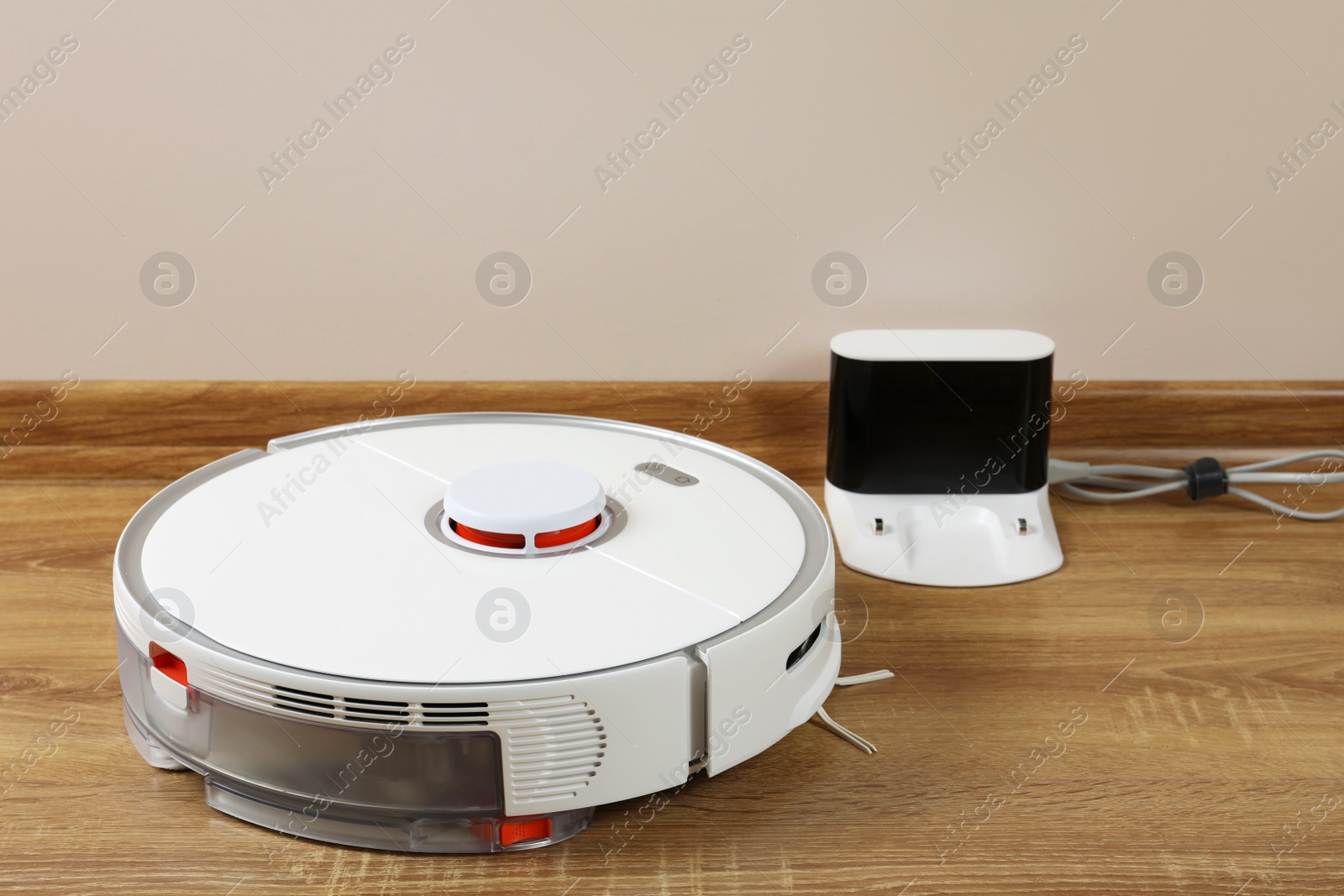 Photo of Robotic vacuum cleaner and charger on wooden floor indoors