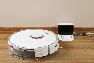 Photo of Robotic vacuum cleaner and charger on wooden floor indoors