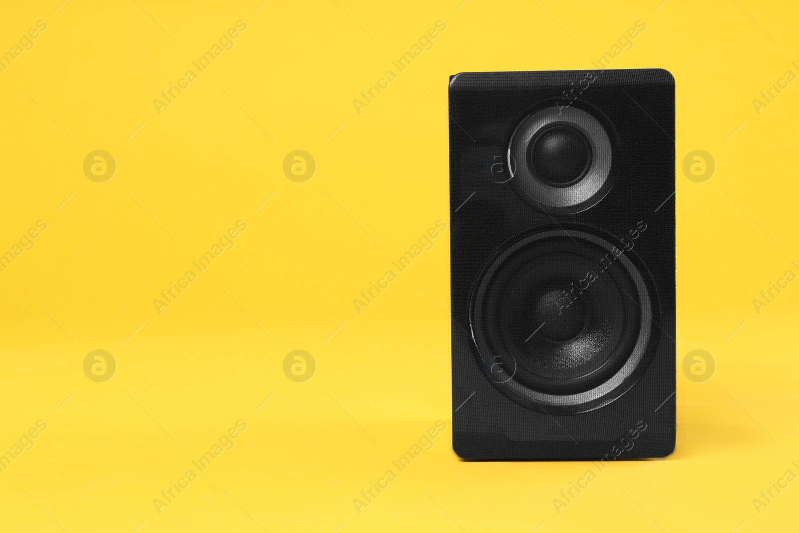 Photo of Modern powerful audio speaker on yellow background, space for text