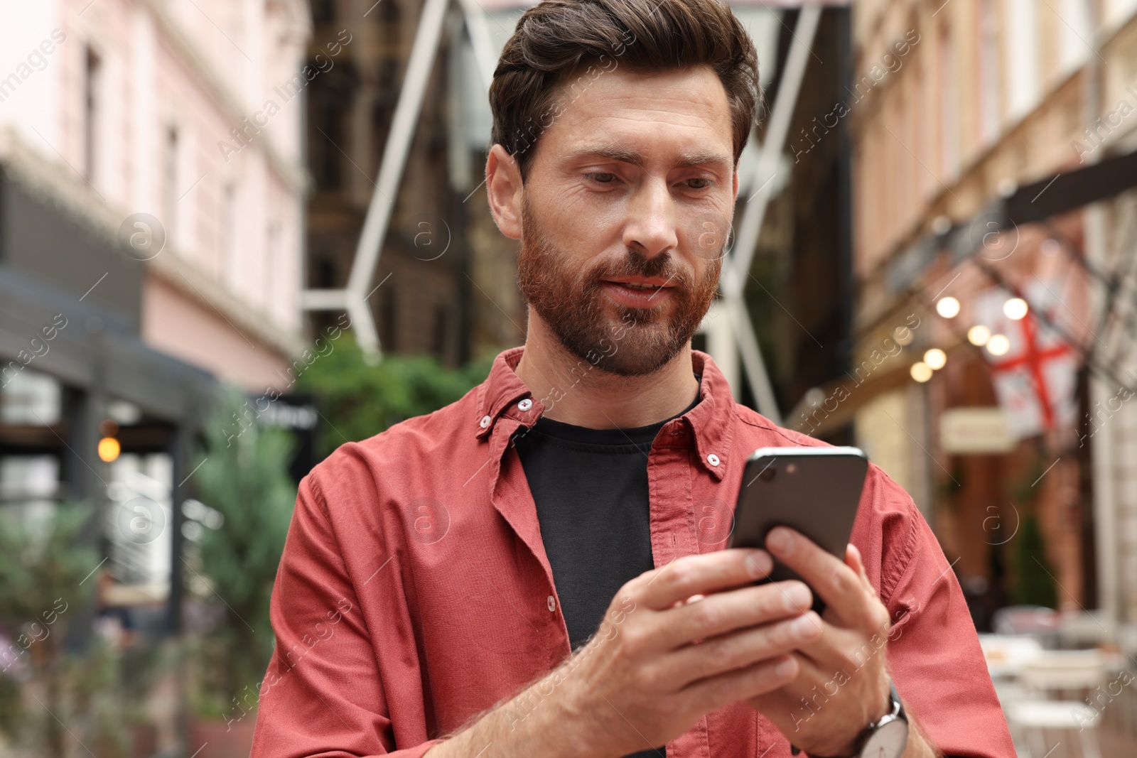 Photo of Handsome man using smartphone on city street