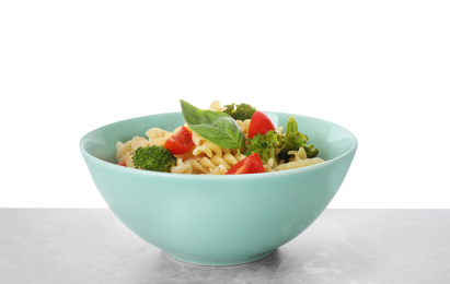 Tasty pasta with broccoli, cherry tomatoes and basil on light grey marble table against white background