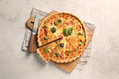 Photo of Delicious homemade vegetable quiche and knife on light gray table, top view
