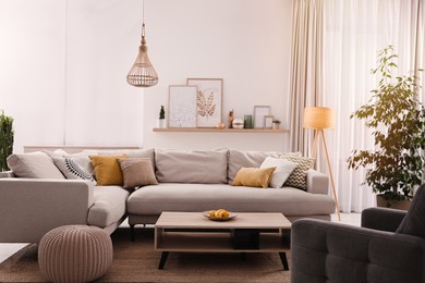 Photo of Stylish living room interior with comfortable grey sofa and coffee table