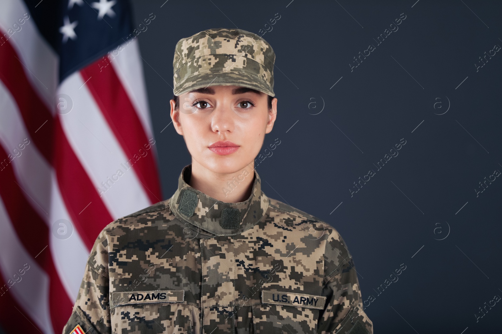 Photo of Female American soldier and flag of USA on dark background. Military service