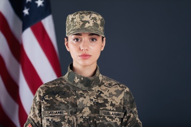 Female American soldier and flag of USA on dark background. Military service