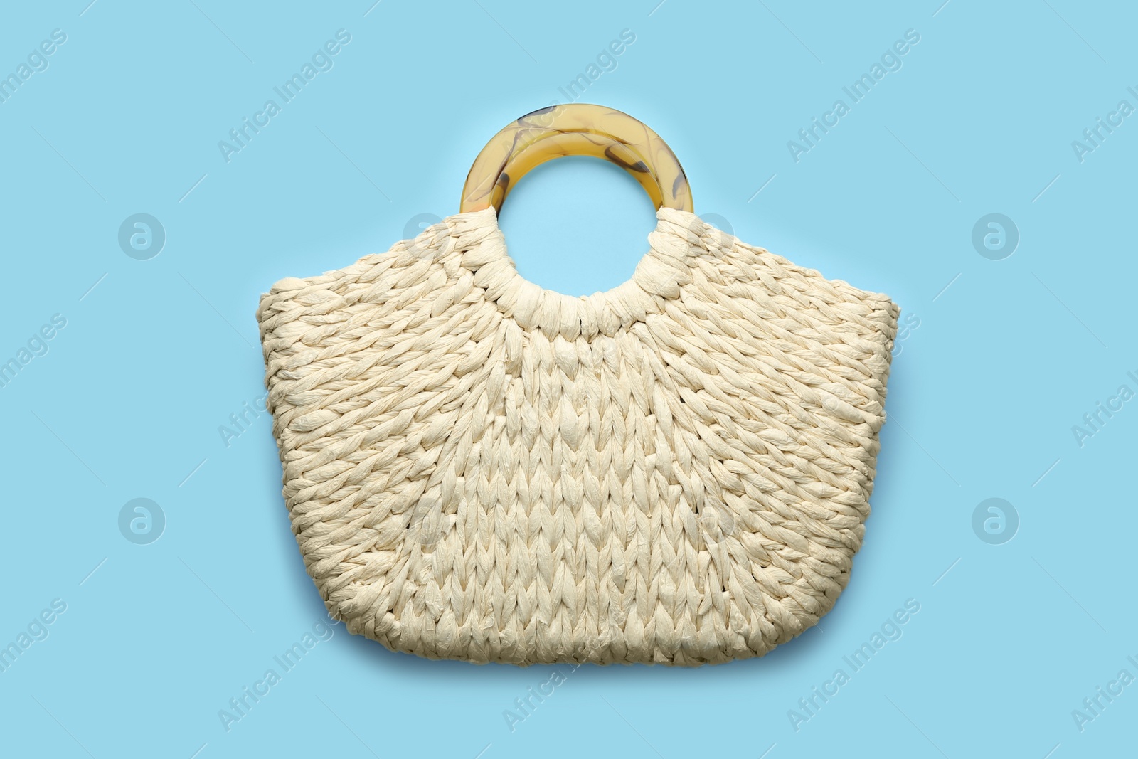 Photo of Elegant woman's straw bag on light blue background, top view