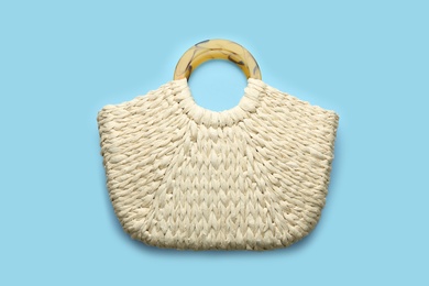 Elegant woman's straw bag on light blue background, top view