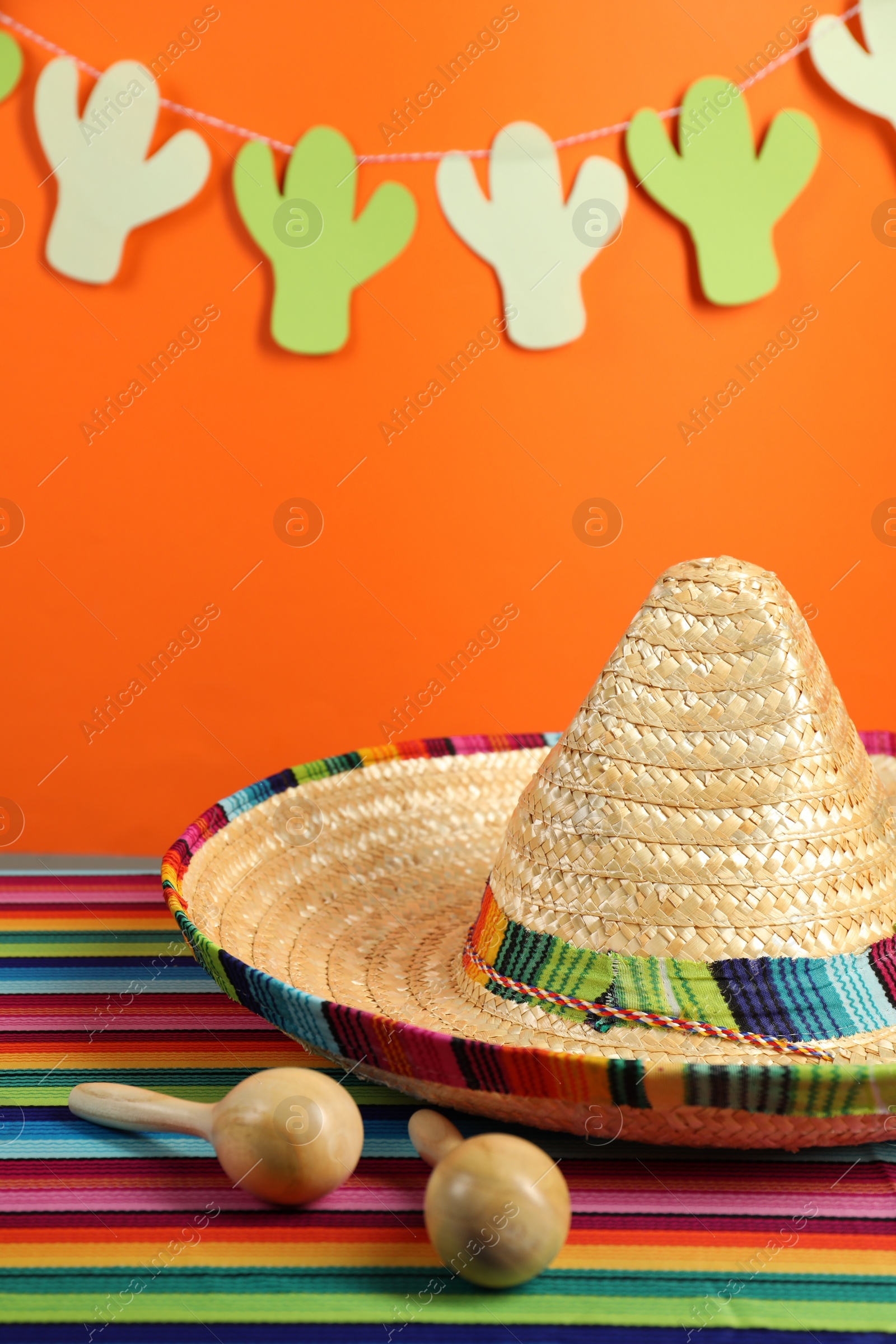 Photo of Mexican sombrero hat and maracas on color table, closeup