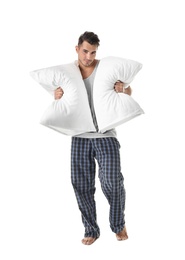 Young man with soft pillows on white background